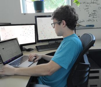 Cody working at his workstation and laptop