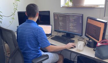 Joey working a his desk with a lot of code on his computer.